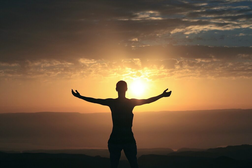 A person giving thanks and feeling gratitude to the setting sun